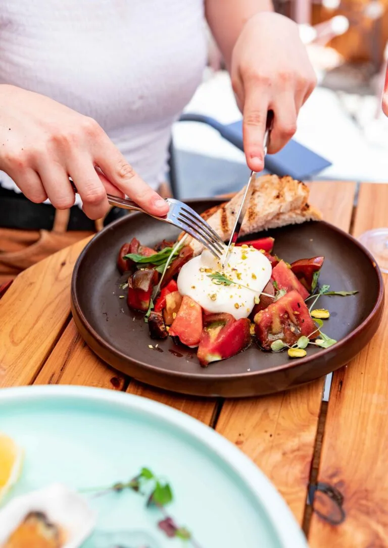Comensales compartiendo un plato de burrata y tomate
