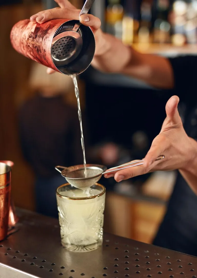 Bartender colando un cóctel en la barra