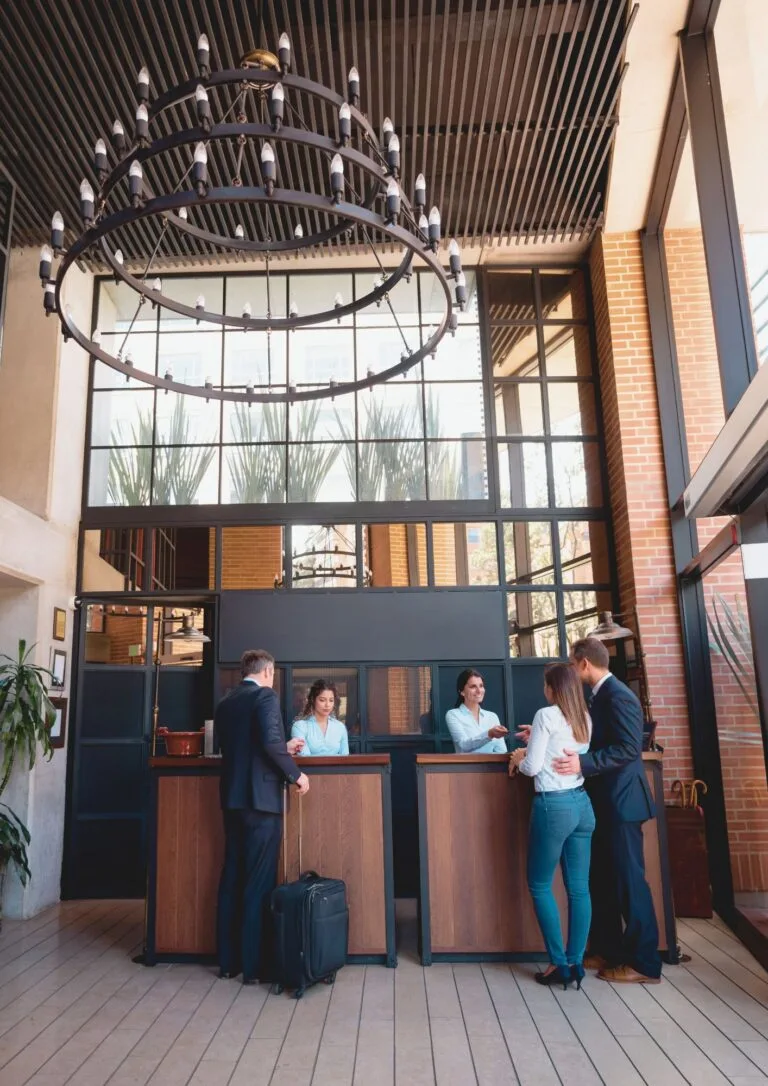 Recepción de hotel con lámpara circular y huéspedes registrándose