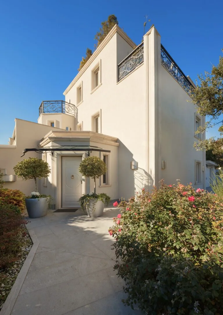 Fachada de villa con entrada ajardinada
