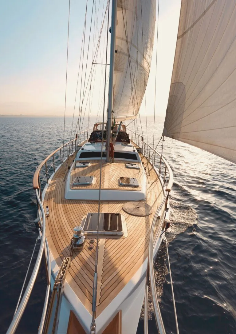 Proa y cubierta de teca de un velero al atardecer