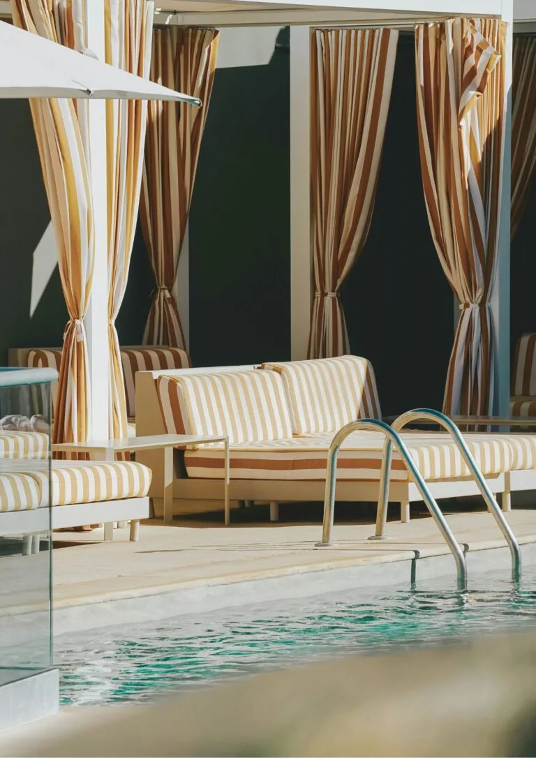 Cama balinesa junto a la piscina con cortinas al viento