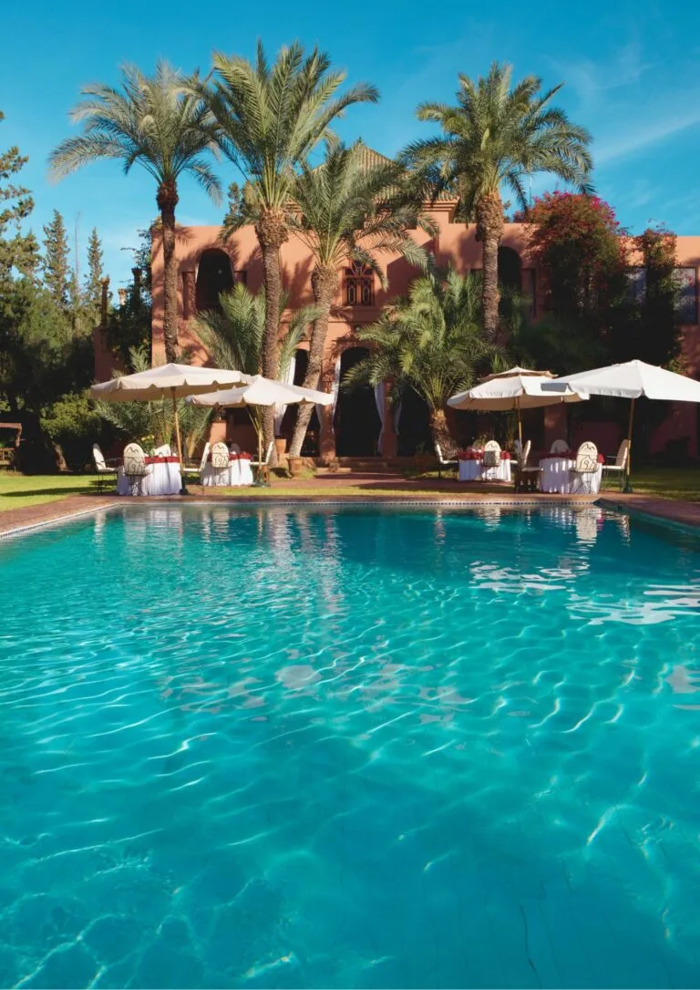 Piscina rodeada de palmeras y sombrillas