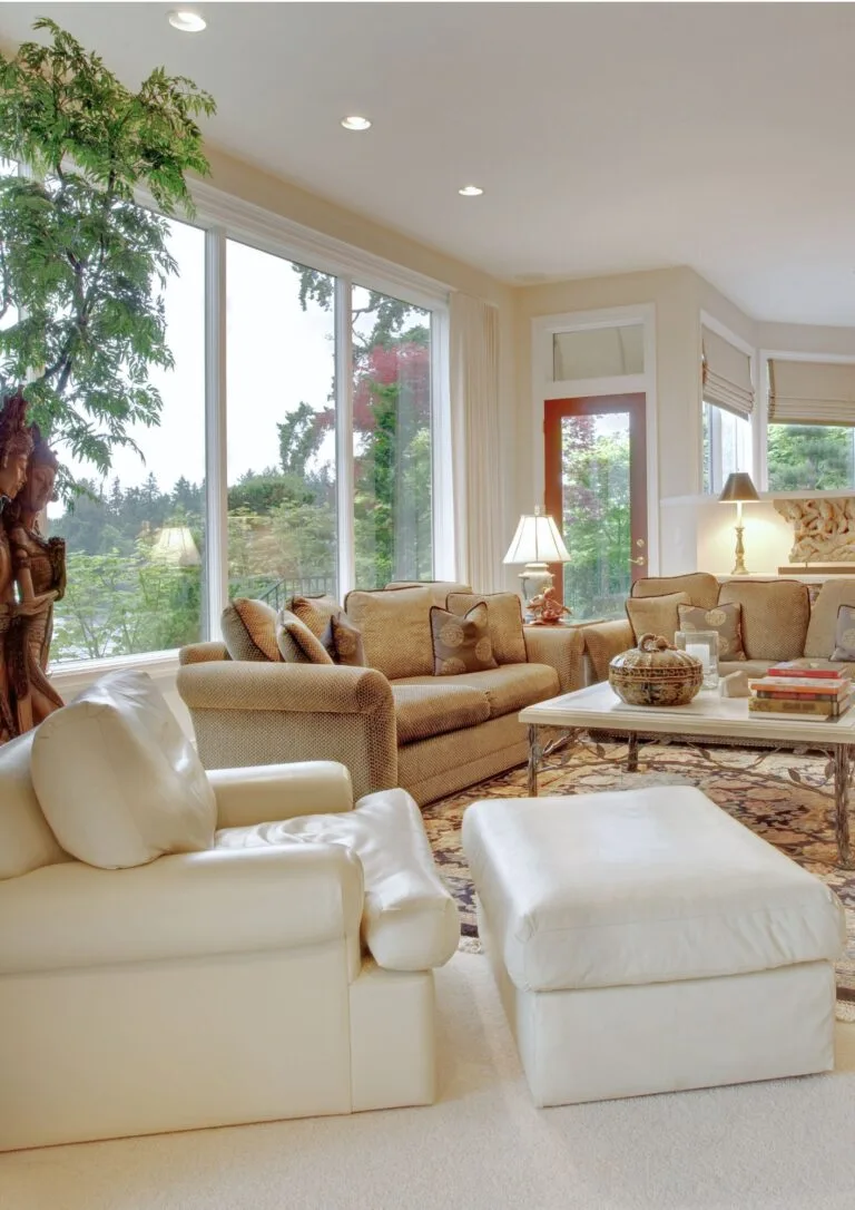Salón luminoso con sofás blancos y ventanal al jardín