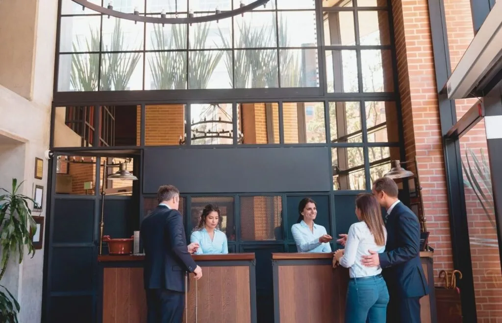 Recepción de un hotel con una lámpara circular de gran tamaño y varias personas conversando junto a la entrada