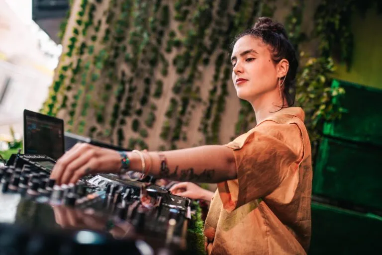DJ mezclando en una cabina rodeada de plantas