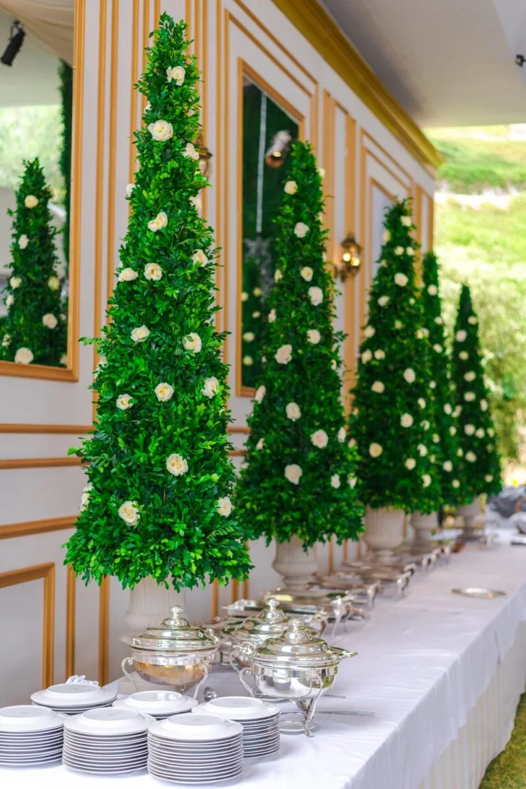 Árboles decorados con rosas blancas junto a la mesa de gala