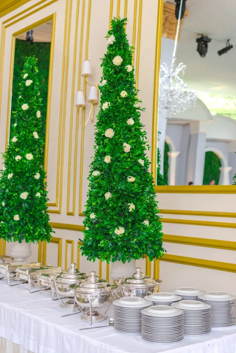 Salón de eventos con topiarios y mesa larga ya montada