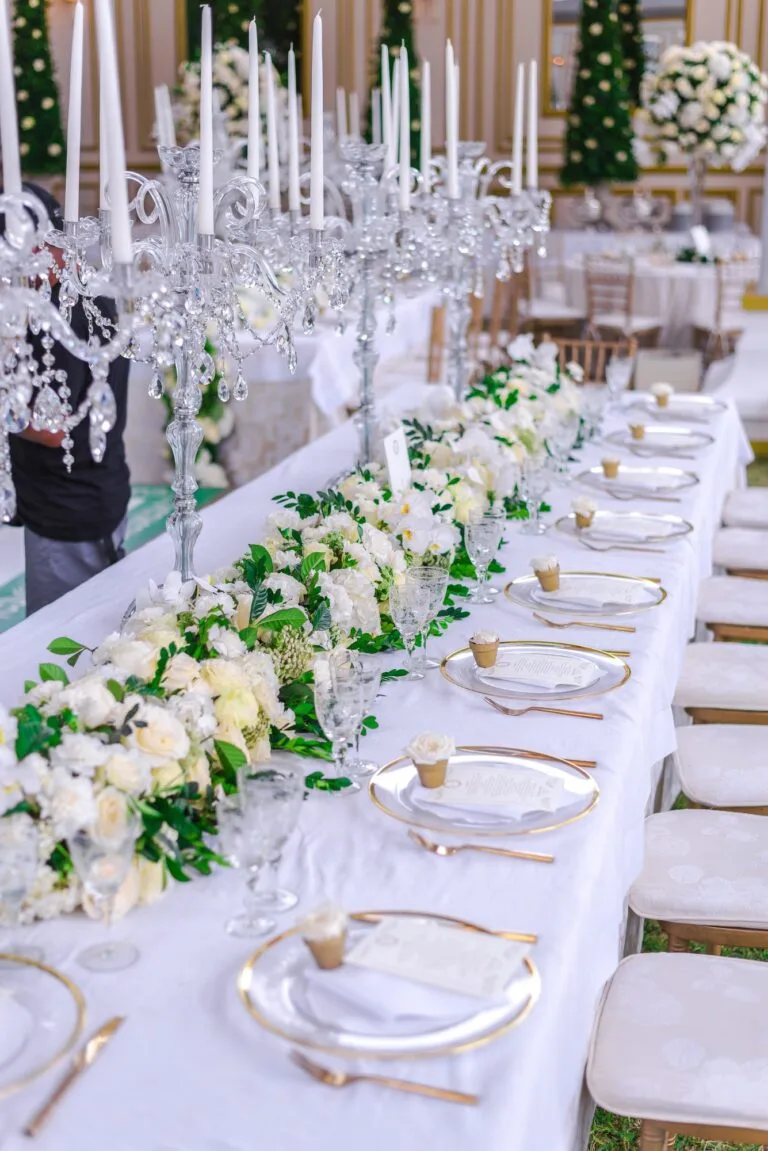 Mesa larga con cubertería dorada y centros florales