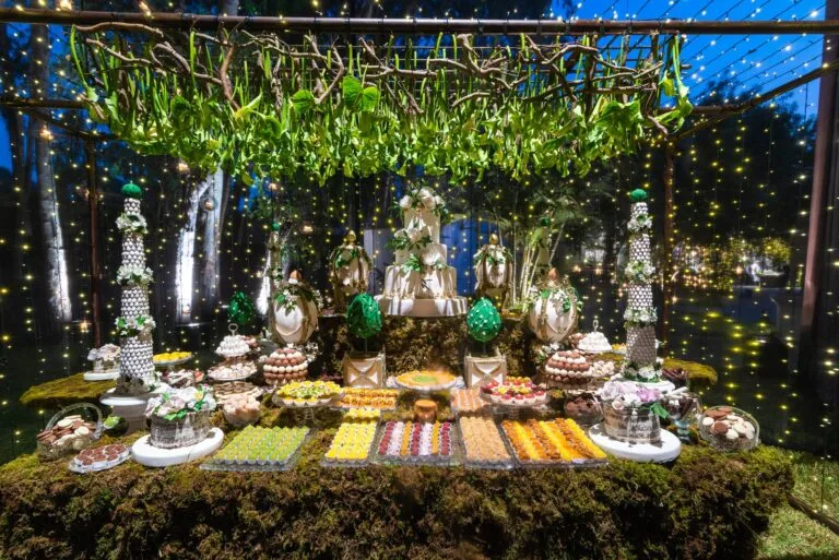 Mesa de postres bajo un techo de plantas colgantes, de noche