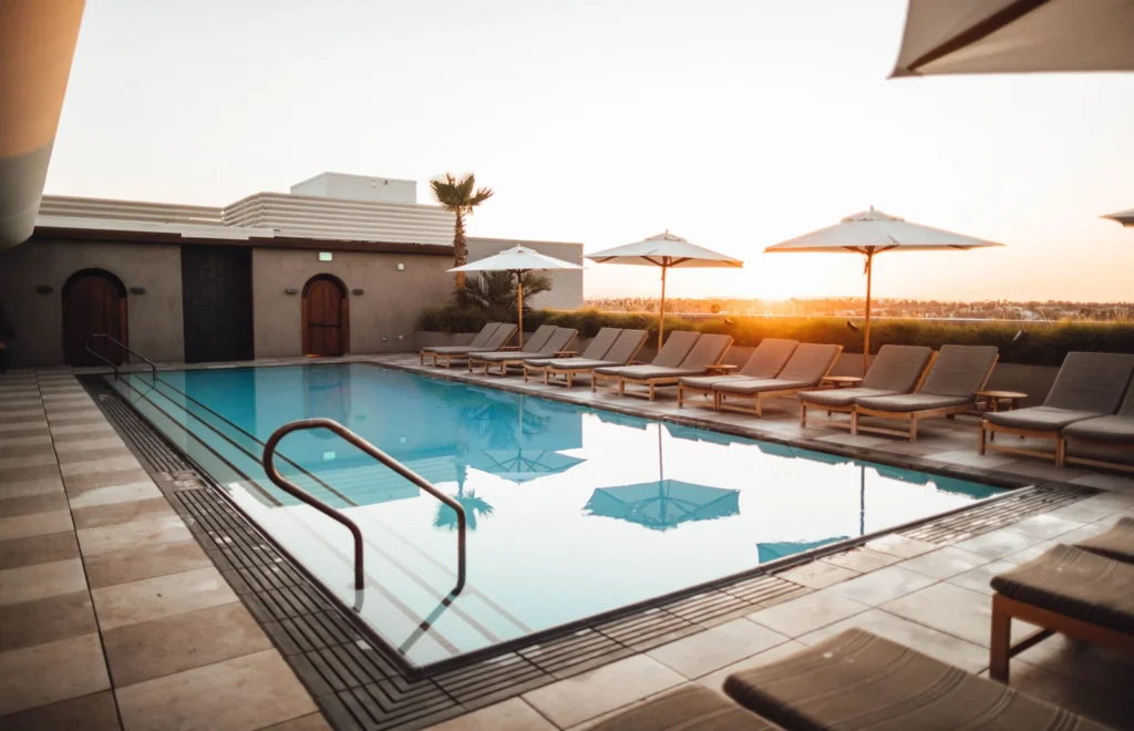 Piscina de un hotel en una azotea al atardecer: la fachada de la izquierda queda en sombra mientras la de la derecha, junto a las tumbonas, recibe sol directo